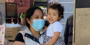 A masked woman holds her toddler daughter