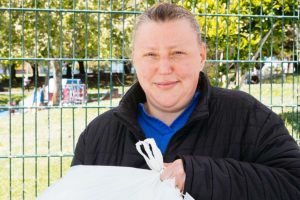 Anna holds her groceries in front of the park