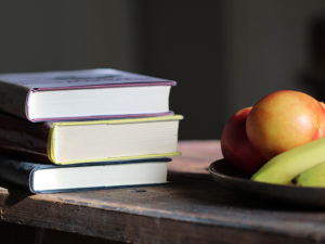 Books and apples on a desk.