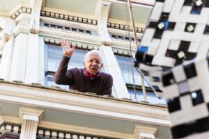 Miguel waves goodbye from his apartment window.