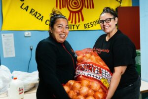 two women holding a large bag of onions