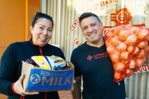 a man and a woman holding produce and food pantry items